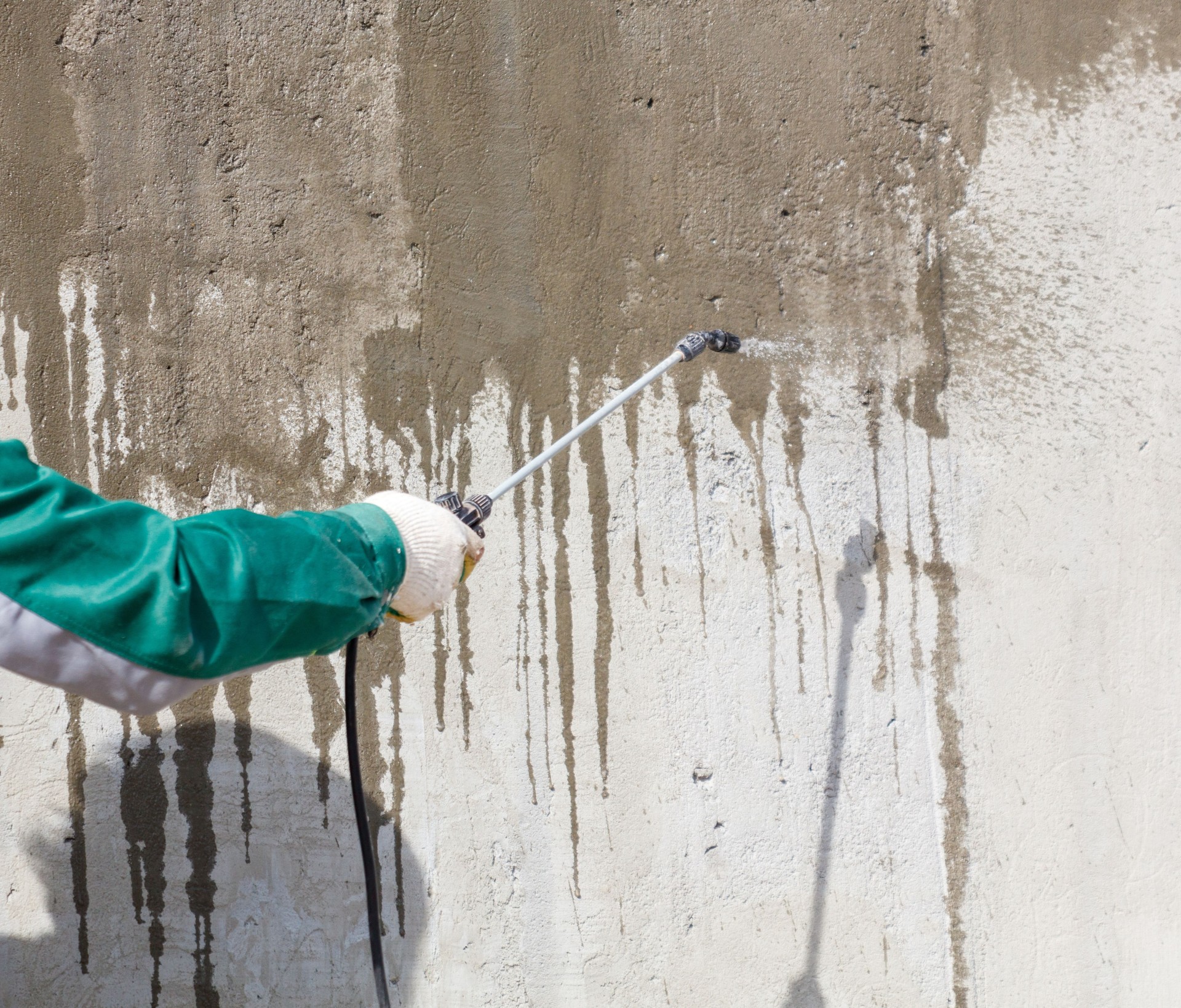 A man is spraying a wall with a spray gun