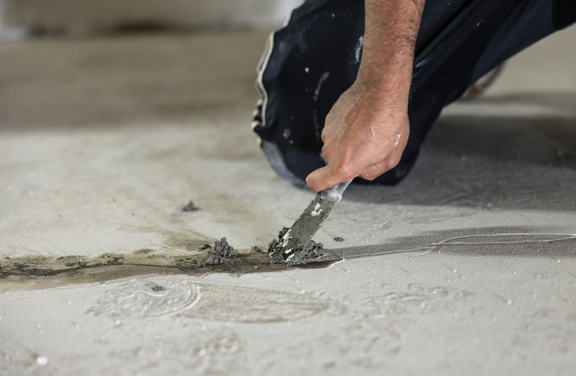 Basement waterproofing. Worker using hydraulic cement for sealing cracks in the basement floor.